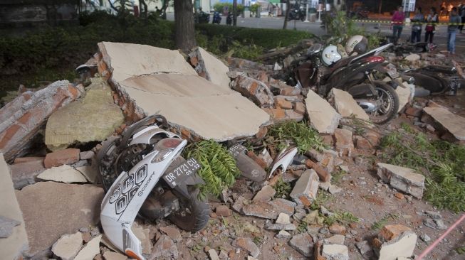 Sejumlah warga melihat reruntuhan bangunan akibat gempa yang menimpa kendaraan di salah satu pusat perbelanjaan di Denpasar, Bali, Minggu (5/8). Gempa tujuh pada skala richter yang berpusat di Lombok, NTB, menyebabkan kerusakan bangunan di berbagai lokasi di Bali dan mengakibatkan sejumlah warga terluka. ANTARA FOTO/Nyoman Budhiana