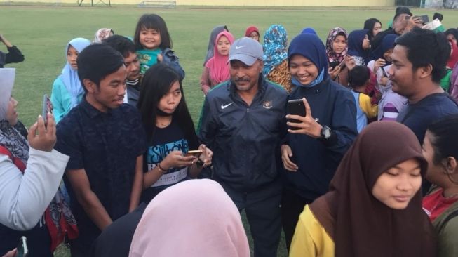 Para fans berebut foto dengan pemain tim nasional Indonesia U-16 Fakhri Husaini saat melakukan latihan di Stadion Jenggolo, Sidoarjo. (Suara.com/Dimas Angga Perkasa) 