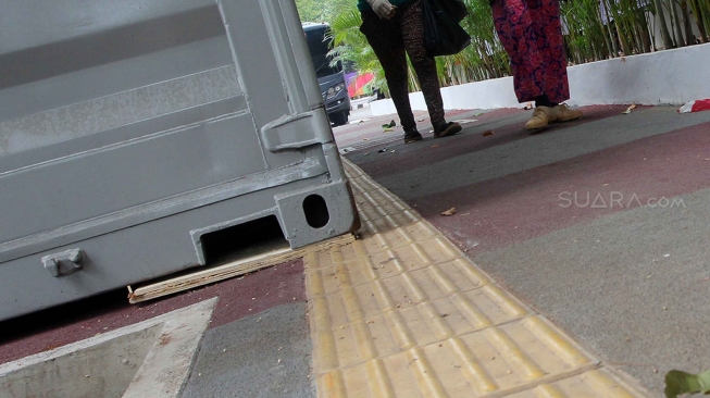 Pejalan kaki melintas di samping kontainer penjualan tiket Asian Games 2018 yang berada di trotoar Jalan Pintu Satu Senayan, kawasan Gelora Bung Karno (GBK), Jakarta, Rabu (8/8). [Suara.com/Oke Atmaja]