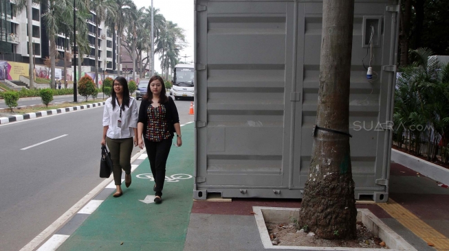 Pejalan kaki melintas di samping kontainer penjualan tiket Asian Games 2018 yang berada di trotoar Jalan Pintu Satu Senayan, kawasan Gelora Bung Karno (GBK), Jakarta, Rabu (8/8). [Suara.com/Oke Atmaja]