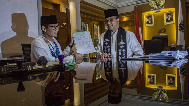 Gubernur DKI Jakarta Anies Baswedan (kanan) dan Sandiaga Uno (kiri) menunjukkan surat pengunduran diri Sandiaga sebagai Wagub DKI Jakarta di Balai Kota, Jakarta, Jumat (10/8). ANTARA FOTO/Galih Pradipta