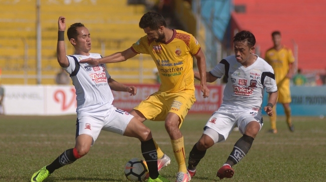 Pesepakbola Sriwijaya FC Manuchehr Jalilov (tengah) berebut bola dengan dua pemain Madura United FC pada pertandingan lanjutan Gojek Liga1 di Stadion GOR H Agus Salim, Padang, Sumatera Barat, Sabtu (11/8). Sriwijaya FC dikalahkan Madura United FC dengan skor 1-2. ANTARA FOTO/Iggoy el Fitra