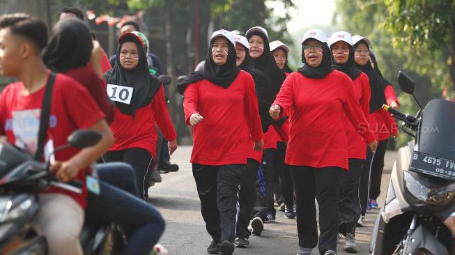 Sejumalah warga mengikuti lomba gerak jalan di kelurahan Kelapa Dua Wetan, Jakarta Timur, Minggu (12/8). Perlombaan tersebut untuk menyambut HUT ke-73 RI. [Suara.com/Muhaimin A Untung]