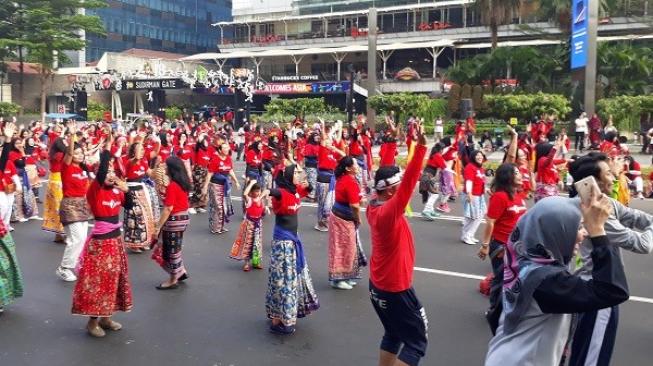 Yayasan Belantara Budaya Indonesia menggelar flashmob Tarian Nusantara yang diikuti ribuan peserta menyambut HUT RI ke-73 sekaligus Asian Games 2018 di area car free day, Minggu (12/8/2018). (Suara.com/Risna Halidi)