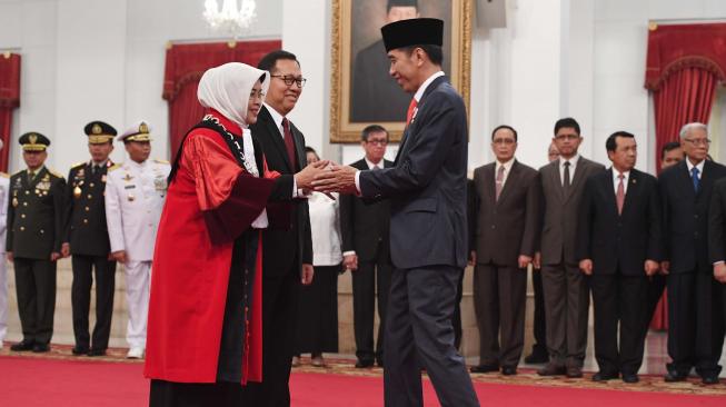 Presiden Joko Widodo (kanan) memberi ucapan selamat kepada Hakim Mahkamah Konstitusi Enny Nurbaningsih (kiri) seusai pelantikan di Istana Negara, Jakarta, Senin (13/8). ANTARA FOTO/Puspa Perwitasari