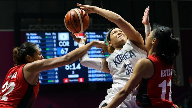 Pebasket Korea, Kim Hanbyul (tengah) melakukan jump shot ditengah hadangan dua pemain Indonesia, Dyah Lestari (11) dan Gabriel Sophia (22), dalam penyisihan Grup X Asian Games 2018 di Hall Basket Senayan, Jakarta Rabu (15/8). [INASGOC/Rocky Padila]