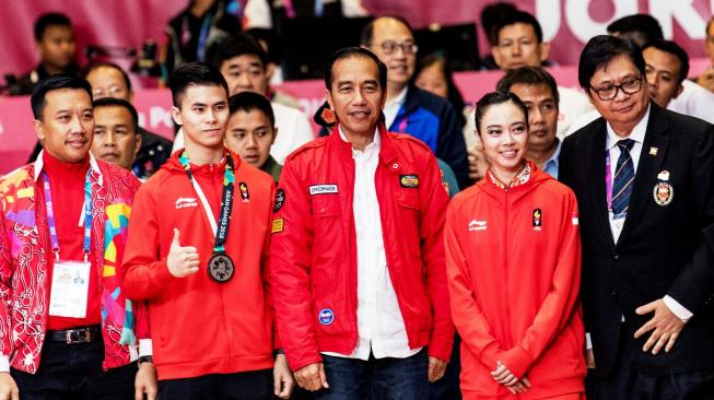 Presiden Joko Widodo (Jokowi) didampingi Menpora Imam Nahrawi dan Ketua Umum PB Wushu Indonesia, Airlangga Hartarto (kanan), berfoto bersama atlet wushu putri peraih medali emas Lindswell Kwok dan atlet wushu putra peraih medali perak Edgar Xavier Marvelo (kedua kiri), di sela-sela pertandingan wushu Asian Games 2018 di JIExpo, Kemayoran, Jakarta, Senin (20/8/2018). [Antara/INASGOC/Ismar Patrizki]