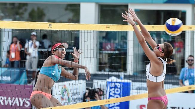 Atlet voli pantai putri Indonesia, Dhita Juliana (kiri), melakukan smes ke arah pevoli Hong Kong, Yuen Mei Wong, pada pertandingan babak penyisihan Pool D voli pantai putri Asian Games 2018 di arena Jakabaring Sport City (JSC), Palembang, Minggu (19/8/2018). [Antara/INASGOC/Muhammad Adimaja]