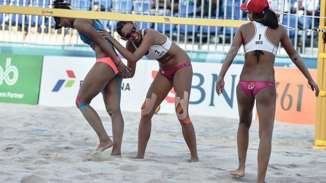 Atlet voli pantai putri Indonesia, Putu Dini Jasita Utami (kiri), bergurau dengan lawannya asal Hong Kong, Yuen Mei Wong (tengah) dan Tin Lai Ng (kanan), pada pertandingan babak penyisihan Pool D voli pantai putri Asian Games 2018 di arena Jakabaring Sport City (JSC), Palembang, Minggu (19/8/2018). [Antara/INASGOC/Muhammad Adimaja]