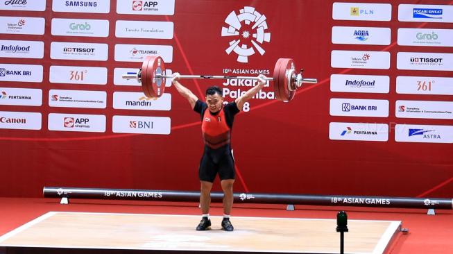 Lifter Indonesia, Eko Yuli Irawan melakukan angkatan snatch dalam pertandingan angkat besi kelas 62 kg putra Asian Games 2018 di Hall A JIExpo, Kemayoran, Jakarta, Selasa (21/8). [Suara.com/Dendi Afriyan]