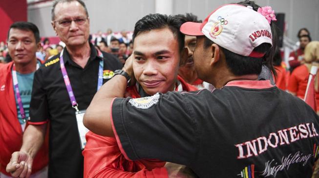 Lifter Indonesia Eko Yuli Irawan (tengah) mendapat ucapan selamat dari ayahnya, Saman (kanan)usai bertanding pada nomor angkat besi putra 62 kg Asian Games ke-18 2018 di JiExpo, Jakarta, Selasa (21/8).  ANTARA FOTO/INASGOC/Dhemas Reviyanto