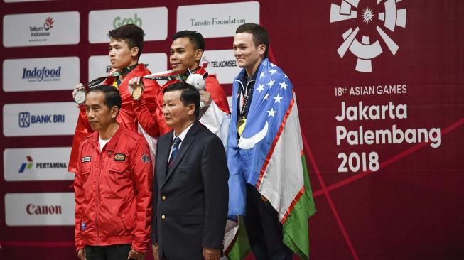 Presiden Joko Widodo (kiri bawah) berfoto bersama Lifter Indonesia peraih medali emas Eko Yuli Irawan (tengah atas), Lifter Vietnam Van Vinh Trinh (kiri atas) dan Lifter Uzbekistan Adkhamjon Ergashev (kanan atas) berfoto bersama pada upacara penyerahan medali angkat besi putra 62 kg Asian Games ke-18 2018 di JiExpo, Jakarta, Selasa (21/8). ANTARA FOTO/INASGOC/Dhemas Reviyanto