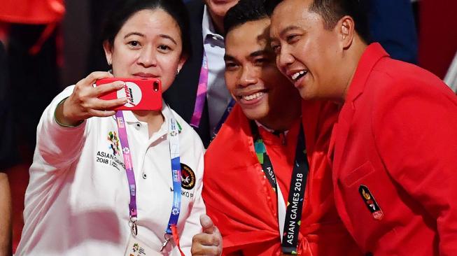 Menko PMK Puan Maharani (kiri) dan Menpora Imam Nahrawi (kanan) berswafoto bersama lifter Indonesia Eko Yuli Irawan (tengah) yang meraih emas pada nomor angkat besi putra 62 kg Group A Asian Games ke-18 2018 di JiExpo Jakarta, Selasa (21/8). ANTARA FOTO/INASGOC/Fanny Octavianus