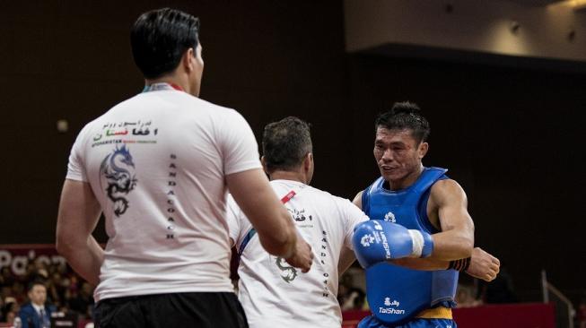 Atlet Sanda Indonesia Puja Riyaya (kanan) memberi hormat kepada pelatih dan ofisial petarung lawan dari Afganistan pada babak perdelapan final 70 kilogram Sanda Putra Wushu Asian Games 2018 di JIExpo Kemayoran, Jakarta, Minggu (19/8). ANTARA FOTO/INASGOC/Ismar Patrizki