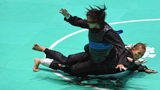 Pesilat Indonesia Wewey Wita (bawah) bertanding melawan pesilat Thailand Suda Lueangaphichatkun (atas) dalam babak perempat final Kelas B Putri Asian Games 2018 di Padepokan Pencak Silat Taman Mini Indonesia Indah (TMII), Jakarta, Jumat (24/8). ANTARA FOTO/INASGOC/Melvinas Priananda