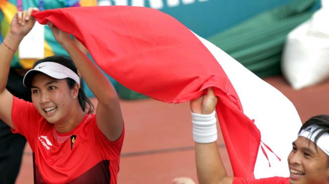 Petenis Indonesia Christopher Benjamin Rungkat (kanan) yang berpasangan dengan Aldila Sutjiadi (kiri) membawa bendera setelah menjadi juara dengan mengalahkan lawannya petenis Thailand Luksika Kumkhum dan Sonchat Ratiwatana pada babak final tenis ganda campuran Asian Games 2018 di JSC Tennis Courts, Palembang, Sumatera Selatan, Sabtu (25/8). ANTARA FOTO/INASGOC/Hendra Syamhari