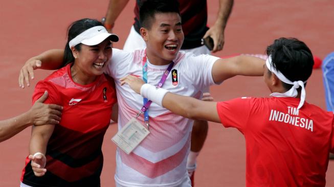 Petenis Indonesia Christopher Benjamin Rungkat (kanan) yang berpasangan dengan Aldila Sutjiadi (kiri) beraksi setelah menjadi juara dengan mengalahkan lawannya petenis Thailand Luksika Kumkhum dan Sonchat Ratiwatana pada babak final tenis ganda campuran Asian Games 2018 di JSC Tennis Courts, Palembang, Sumatera Selatan, Sabtu (25/8). ANTARA FOTO/INASGOC/Hendra Syamhari