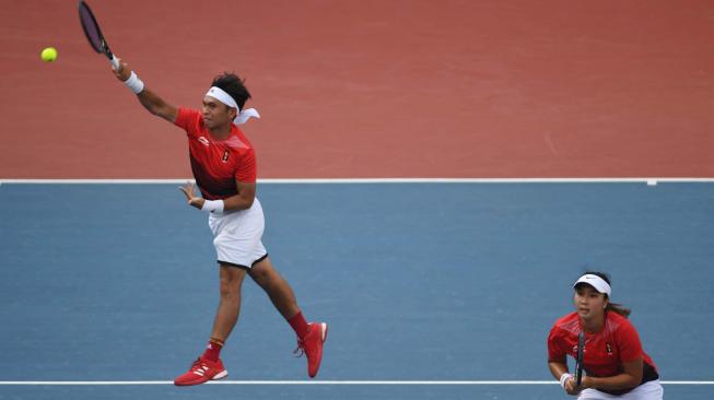 Ganda campuran Indonesia Christopher Rungkat yang berpasangan dengan Aldila Sutjiadi mengembalikan bola ke petenis Thailand Luksika Kumkhum dan Sonchat Ratiwatana pada final tenis ganda campuran Asian Games 2018 di Jakabaring Sport City, Palembang, Sumatera Selatan, Sabtu (25/8). ANTARA FOTO/INASGOC/Wahyu Putro A