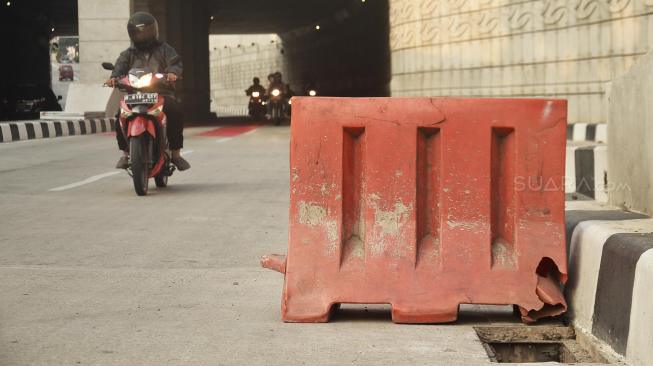 Kendaraan melintas di samping penutup saluran air atau "steel grating" yang hilang di jalur Lintas Bawah Mampang-Kuningan, Jakarta, Sabtu (25/8). [Suara.com/Muhaimin A Untung]