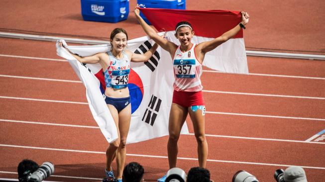 Pelari Korea Selatan Hyelim Jung (kiri) bersama pelari Indonesia Emilia Nova (kanan) merayakan kemenangan seusai Final nomor lari gawang 100 meter putri Asian Games 2018 di Stadion Gelora Bung Karno, Senayan, Jakarta, Minggu (26/8). ANTARA FOTO/INASGOC/M Agung Rajasa