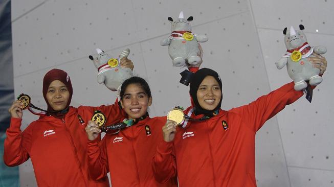 Regu panjat tebing Indonesia Puji Lestari (kiri), Rajiah Sallsabillah (tengah) dan Aries Susanti Rahayu (kanan)memperlihatkan medali emas setelah menjadi pemenang pada final speed relay putri Asian Games 2018 di Arena Panjat Tebing Jakabaring, Palembang, Sumatera Selatan, Senin (27/8). ANTARA FOTO/INASGOC/Rahmad Suryadi/nym/18