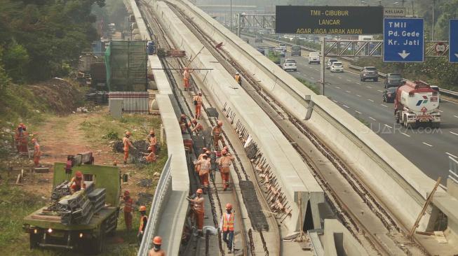 Pekerja menyelesaikan proyek pembangunan kereta ringan atau Light Rail Transit (LRT) rute Cibubur-Cawang di Tol Jagorawi, Cibubur, Jakarta, Senin (27/8). [Suara.com/Muhaimin A Untung]