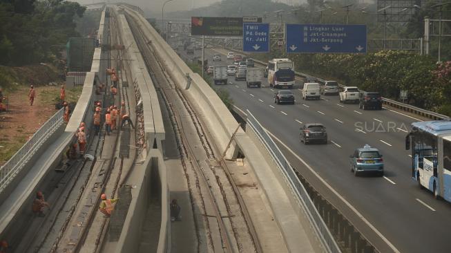 Pekerja menyelesaikan proyek pembangunan kereta ringan atau Light Rail Transit (LRT) rute Cibubur-Cawang di Tol Jagorawi, Cibubur, Jakarta, Senin (27/8). [Suara.com/Muhaimin A Untung]