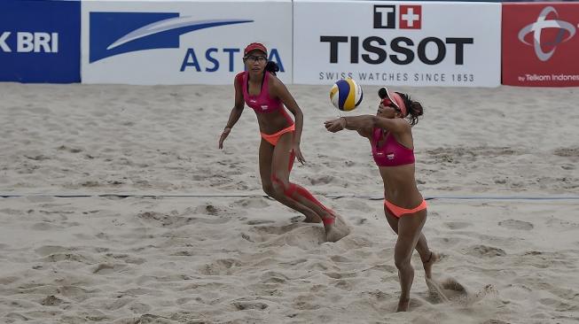 Pevoli pantai wanita Indonesia Putu Dini Jasita Utami (kanan) dan Dhita Juliana (kiri) mencoba mengembalikan bola ke arah pevoli Cina pada pertandingan babak semifinal voli pantai wanita Asian Games 2018 di arena Jakabaring Sport City, Palembang, Sumsel, Minggu (26/8). ANTARA FOTO/INASGOC/Muhammad Adimaja