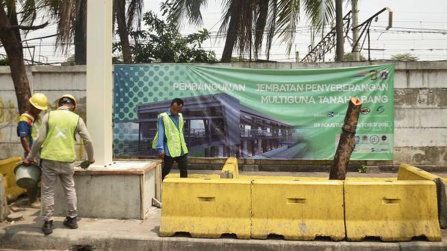 Pekerja menyelesaikan di antara proyek pembangunan Jembatan Penyeberangan Multiguna atau "Skybridge" di Tanah Abang, Jakarta, Selasa (28/8). [Suara.com/Muhaimin A Untung]