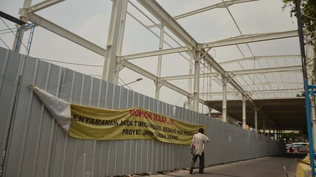 Warga melintas di antara proyek pembangunan Jembatan Penyeberangan Multiguna atau "Skybridge" di Tanah Abang, Jakarta, Selasa (28/8). [Suara.com/Muhaimin A Untung]