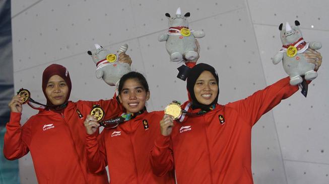 Regu panjat tebing Indonesia Puji Lestari (kiri), Rajiah Sallsabillah (tengah) dan Aries Susanti Rahayu (kanan)memperlihatkan medali emas setelah menjadi pemenang pada final speed relay putri Asian Games 2018 di Arena Panjat Tebing Jakabaring, Palembang, Sumatera Selatan, Senin (27/8). ANTARA FOTO/INASGOC/Rahmad Suryadi