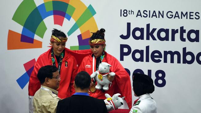 Ketua PB IPSI (Ikatan Pencak Silat Indonesia) Prabowo Subianto (kiri bawah) memberikan medali emas kepada pasangan pesilat Indonesia peraih medali emas Ayu Sidan Wilantari (kiri atas) dan Ni Made Dwiyanti (kanan atas) saat upacara penyerahan medali nomor ganda putri pencak silat seni Asian Games 2018 di Padepokan Pencak Silat Taman Mini Indonesia Indah (TMII), Jakarta, Rabu (29/8). ANTARA FOTO/INASGOC/Melvinas Priananda