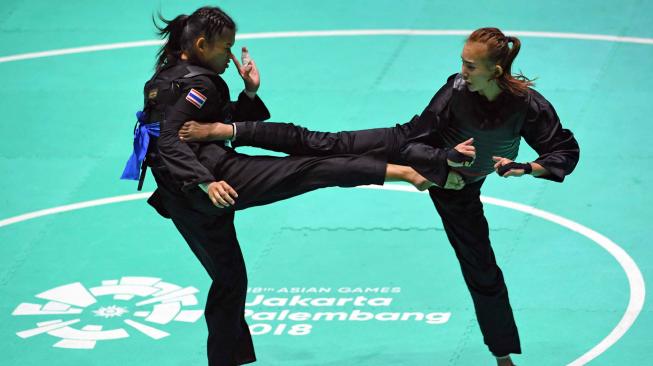 Pesilat Indonesia Wewey Wita (kanan) bertanding melawan pesilat Thailand Suda Lueangaphichatkun (kiri) dalam babak perempat final Kelas B Putri Asian Games 2018 di Padepokan Pencak Silat Taman Mini Indonesia Indah (TMII), Jakarta, Jumat (24/8). ANTARA FOTO/INASGOC/Melvinas Priananda