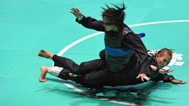 Pesilat Indonesia Wewey Wita (bawah) bertanding melawan pesilat Thailand Suda Lueangaphichatkun (atas) dalam babak perempat final Kelas B Putri Asian Games 2018 di Padepokan Pencak Silat Taman Mini Indonesia Indah (TMII), Jakarta, Jumat (24/8). ANTARA FOTO/INASGOC/Melvinas Priananda