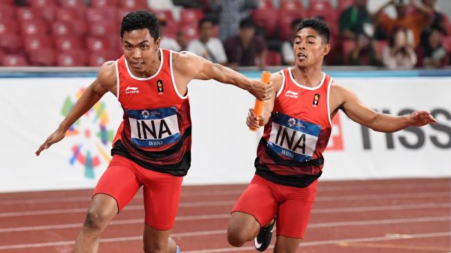 Pelari Indonesia Fadlin (kanan) menyerahkan tongkat kepada Lalu Muhammad Zohri pada babak penyisihan Lari Estafet 4x100m Putra Asian Games ke-18 Tahun 2018 di Stadion Utama Gelora Bung Karno Senayan, Jakarta, Rabu (29/8). ANTARA FOTO/INASGOC/Andika Wahyu