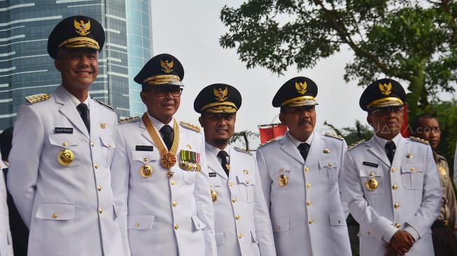 Menteri Dalam Negeri Tjahjo Kumolo beserta Gubernur Sulawesi Selatan Nurdin Abdullah, Wakil Gubernur Sulawesi Selatan Sudirman Sulaiman, Gubernur Jawa Barat Ridwan Kamil, Gubernur Jawa Tengah Ganjar Pranowo, Wakil Gubernur Jateng Taj Yasin Maimoen, Gubernur Bali I Wayan Koster, dan Wakil Gubernur Bali Tjokorda Oka Artha Ardhana Sukawati berjalan sebelum melakukan pertemuan dengan pimpinan KPK di Gedung KPK, Jakarta, Rabu (5/9). [Suara.com/Muhaimin A Untung]