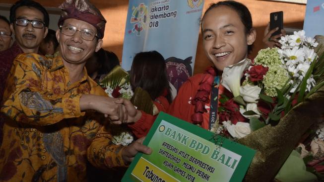 Penjabat Gubernur Bali Hamdani (kedua kiri) berfoto dengan peraih medali perak cabang olahraga skateboard Asian Games 2018, Sanggoe Dharma Tanjung (kanan), saat tiba di Bandara I Gusti Ngurah Rai, Badung, Bali, Senin (3/9). [Antara/Fikri Yusuf]