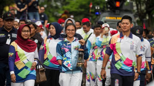 Atlet Para Games Indonesia, Nanda Mei Sholihah (tengah) bersama Ketua INAPGOC, Raja Sapta Oktohari (kanan) membawa lentera api pada Pawai Api Obor Asian Para Games 2018 di Solo, Jawa Tengah, Rabu (5/9). [Antara/Mohammad Ayudha]