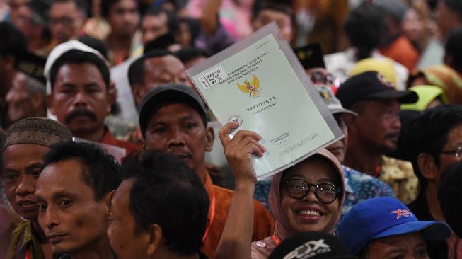 Warga menunjukkan sertifikat tanah miliknya saat penyerahan sertifikat tanah untuk rakyat di Surabaya