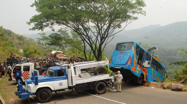 Petugas mengevakuasi mini bus berpenumpang puluhan wisatawan yang masuk jurang di Tanjakan Letter S, Kampung Bantarselang, Kecamatan Cikidang, Sukabumi, Jawa Barat