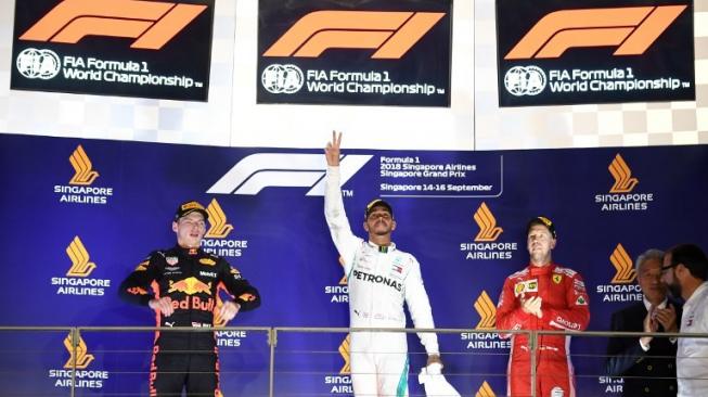 Pemenang GP F1 Singapura, driver Mercedes Lewis Hamilton (tengah) merayakannya bersama driver Red Bull Belanda, Max Verstappen (kiri) dan pembalap Ferrari di podium ketiga, Sebastian Vettel (16/9/2018) [AFP/Manan Vatsyayana]. 