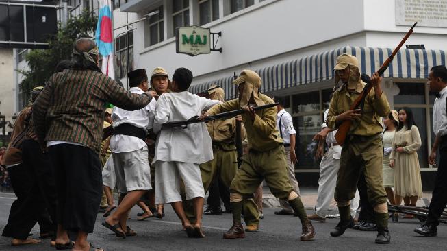 Warga terlibat saling dorong dengan pasukan Jepang di depan Hotel Majapahit saat teatrikal peristiwa perobekan bendera di Hotel Yamato sekarang Hotel Majapahit di Jalan Tunjungan, Surabaya, Jawa Timur, Rabu (19/9). ANTARA FOTO/Zabur Karuru