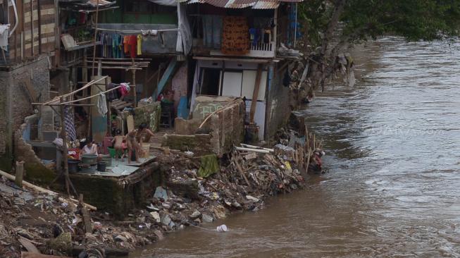 Warga melintas di samping Sungai Ciliwung, Jakarta, Rabu (19/9). [Suara.com/Muhaimin A Untung]