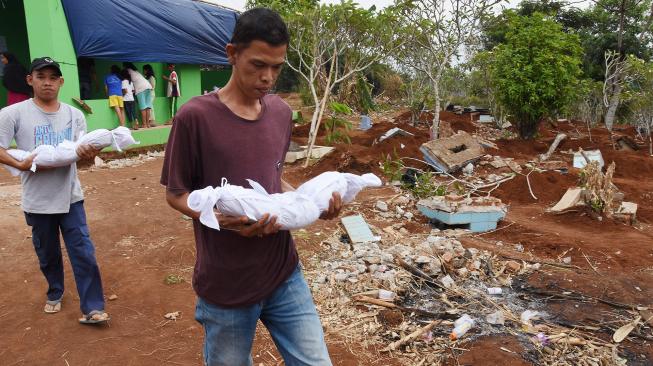 Warga membawa jenazah keluarga mereka untuk dimakamkan kembali saat dilakukan pembongkaran makam di TPU Kumpi Saribah, Limo, Depok, Jawa Barat, Rabu (19/9). [ ANTARA FOTO/Indrianto Eko Suwarso]