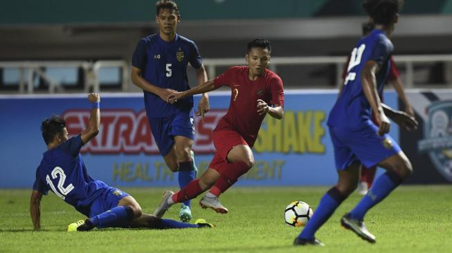 Pesepak bola Timnas U-19 Syahrian Abimanyu (kedua kanan) melewati hadangan pesepak bola Thailand U-19 Chaiwat Weerakijphanich (kiri) saat laga PSSI 88th U19 International Tournament di Stadion Pakansari, Cibinong, Bogor, Jawa Barat, Minggu (23/9). ANTARA FOTO/Hafidz Mubarak A