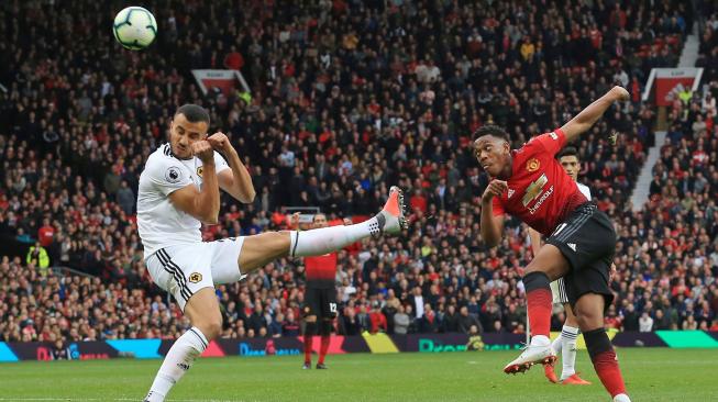 Striker Manchester United Anthony Martial menendang bola dan melewati gelandang asal Wolverhampton Wanderers, Romain Saiss, saat Manchester United melawan Wolverhampton Wanderers di Old Trafford di Manchester, Inggris, Sabtu (22/9). [AFP/Lindsey PARNABY]