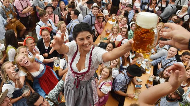 Para peserta mengangkat gelas bir saat pembukaan festival bir terbesar di dunia Oktoberfest ke-185 di Munich, Jerman, Sabtu (22/9). [AFP/Christof STACHE]
