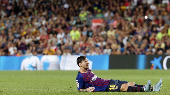 Lionel Messi duduk di lapangan selama pertandingan Barcelona melawan Girona di stadion Camp Nou,Barcelona, Minggu (23/9). [AFP/Pau Barrena] 
