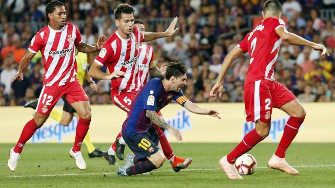 Lionel Messi terjatuh usai dihadang oleh para pemain Girono saat pertandingan Barcelona melawan Girona di Stadion Camp Nou, Barcelona, Spanyol, Minggu (23/9). [AFP/ Pau Barrena]