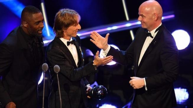 Gelandang Real Madrid dan Timnas Kroasia Luka Modric (tengah) bersalaman dengan Presiden FIFA Gianni Infantino (kanan) setelah Modric memenangkan penghargaan Pemain Terbaik FIFA saat acara di London. Ben STANSALL / AFP